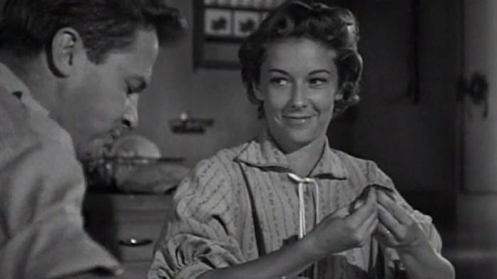 A man and woman sitting at the breakfast table, the woman is smiling.
