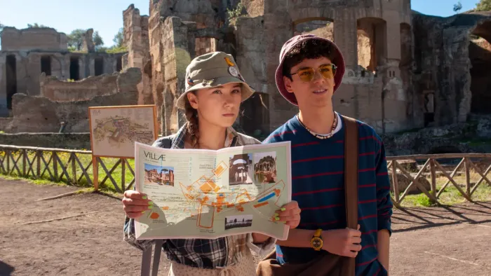 Home Sweet Rome TV show screenshot 2: Lucy and Nico holding up a map in front of the Roman ruins 