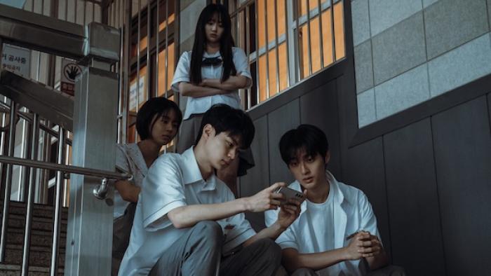 If Wishes Could Kill TV show screenshot 1: A group of high schoolers stand or sit in a stairwell, gathered around a phone and looking concerned