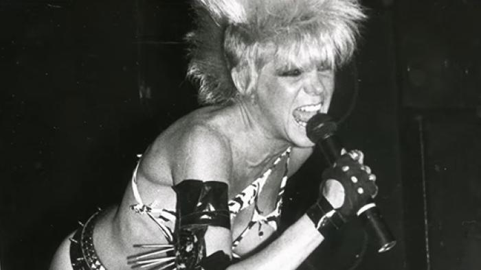 nto the Void TV show screenshot 3: Wendy O. Williams of the band Plasmatics sings into a mic while wearing a zebra-print bikini and punk rock hairdo