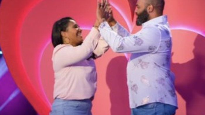 Is it Cake? Valentine's TV show screenshot 3: A couple double high fives each other in front of a giant heart. 