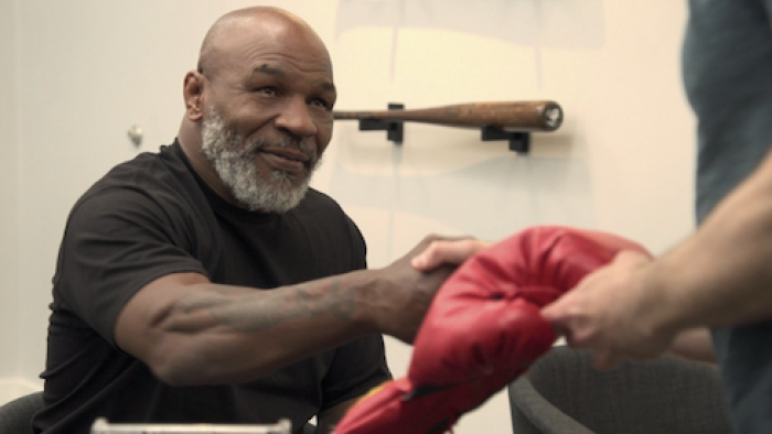 King of Collectibles: The Goldin Touch screenshot 2: Mike Tyson and Ken Goldin each hold a single red boxing glove with one hand. 