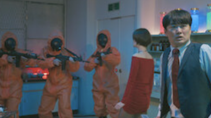 Kiss or Die TV show screenshot 2: Masked men in orange suits aim rifles at woman in red and Gekidan Hitori. 