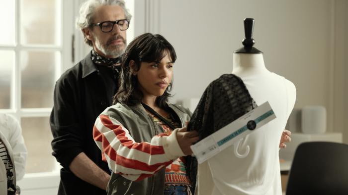 La Maison TV show screenshot 2: Zita Hanrot drapes fabric on a mannequin. Lambert Wilson stands behind.