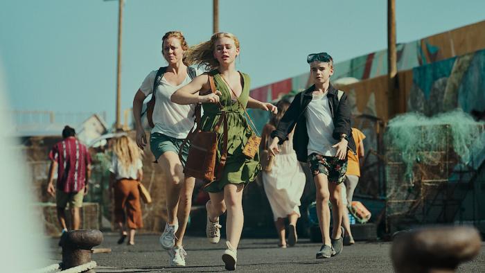 A white woman, her teen daughter and son run through a crowd while wearing warm-weather clothing