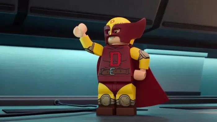 Lego Marvel Avengers Mission Demolition TV show screenshot 1: Dennis in superhero hear with a burgundy eye mask and cape poses as if waving at fans.
