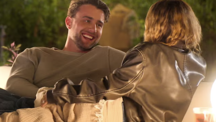 Let's Marry Harry screenshot 2: Harry Bowsey and woman smiling at each other on a couch outdoors.