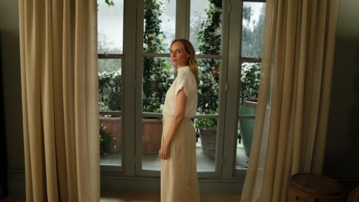Little Disasters TV show screenshot 1: Jess stands in front of a window in an elegant room in a long white dress