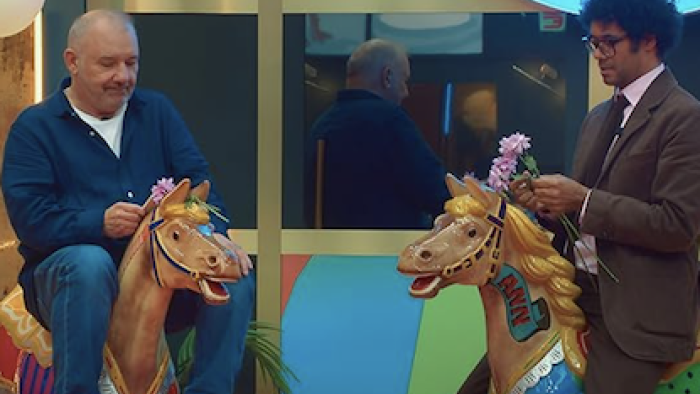 LOL: Last One Laughing UK TV show screenshot 3: Two men sit on carousel horses holding pink flowers.