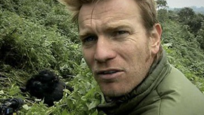 Long Way Down TV show screenshot 2: Ewan McGregor faces camera and gorillas are visible behind his right shoulder.  
