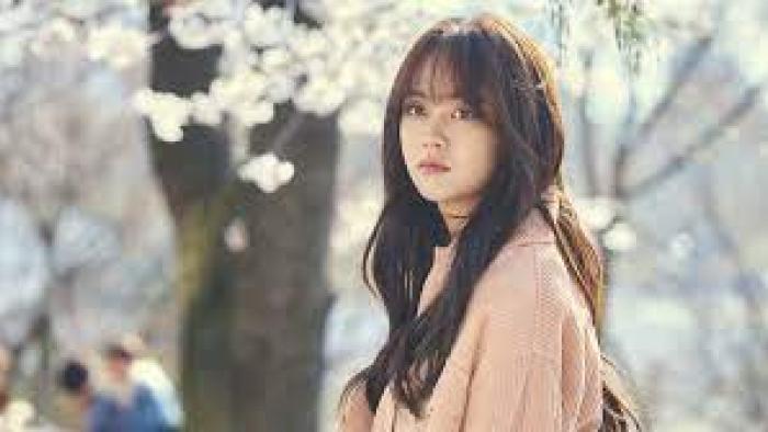 Love Alarm TV show screenshot #3: a young woman stands with a serious expression, with cherry blossoms in the background