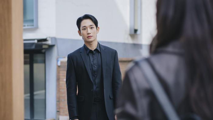 Love Next Door TV show screenshot 3: Jung Hae-in wears an all-black suit while standing in the middle of the street.