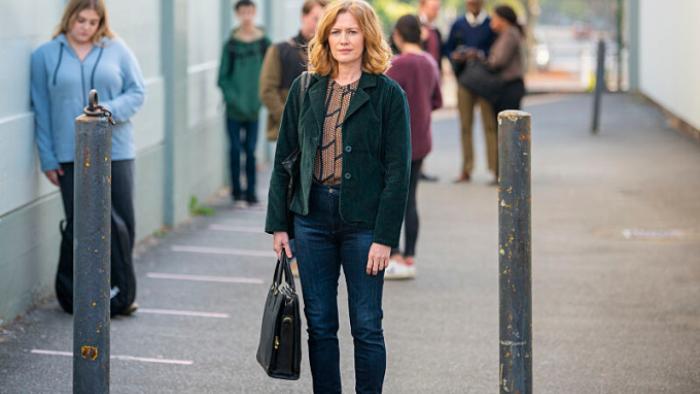 Lucky Hank TV show: Lily walks through a high school hallway, carrying a briefcase; behind her students lounge against walls