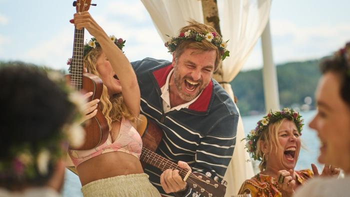 Midsummer Night TV show screenshot 2: Midsummer celebration party guests in floral crowns sing and play the ukulele