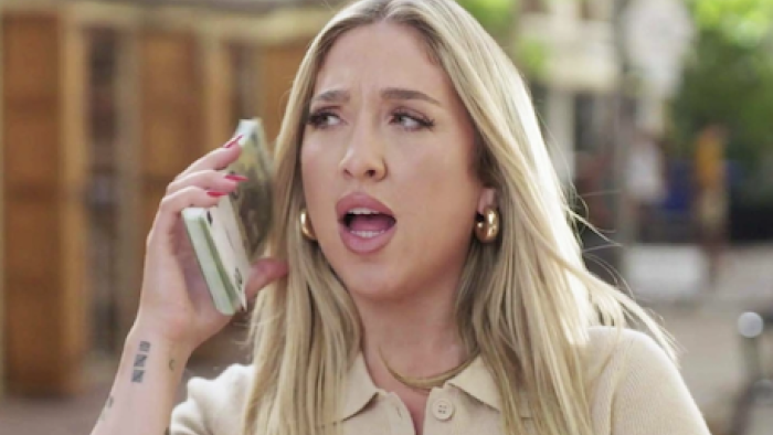 Million Dollar Nannies TV show screenshot 1:Leah Barrs with long blonde hair talking on phone outdoors.