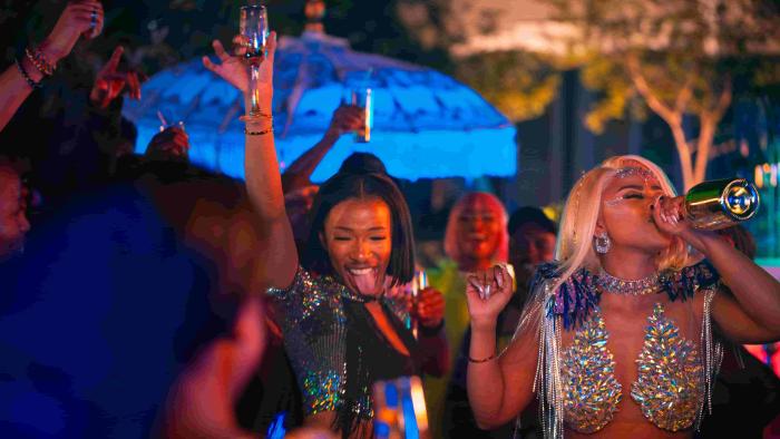 Miseducation TV show screenshot 2: Buntu Petse as Mbali, drinks straight from a bottle while dancing at a party. She wears a holographic top.