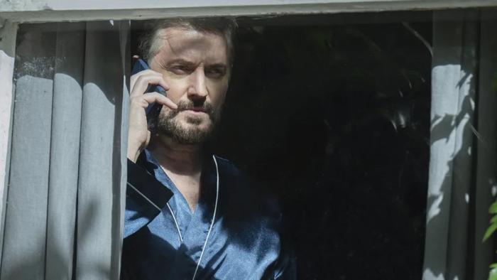 Missing You TV show screenshot 3: Detective Ellis Stagger on his phone in the shadows