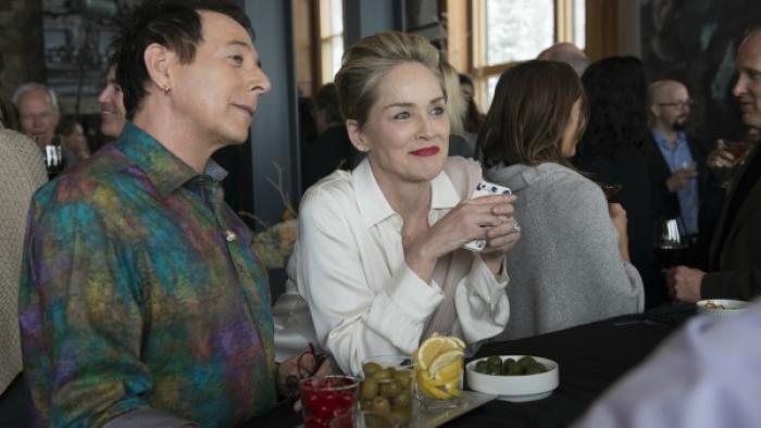 Mosaic Series: A man and a woman are sitting together at a bar, looking at something behind the bar; the woman is smiling and the man looks bemused. 