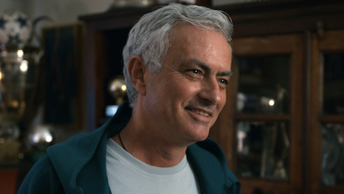 Mourinho TV show screenshot 3: A smiling José Mourinho with gray hair with trophy case in the background.