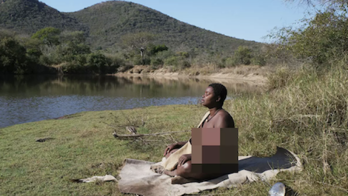 Naked and Afraid: Solo: Shanika Malcolm is a Black-Indigenous woman sitting on blanket facing the sun.