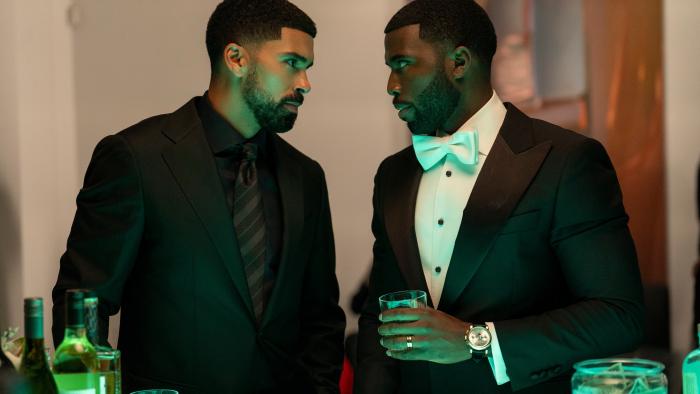  Matthew Law and Y’lan Noel. Law wears an all-black suit with a black striped tie. Noel wears a large white bowtie.