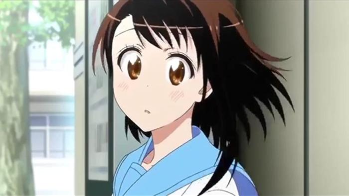 Nisekoi TV show: A girl with brown hair and brown eyes stands outside behind a park building, she is slightly blushing and looks like she is daydreaming.
