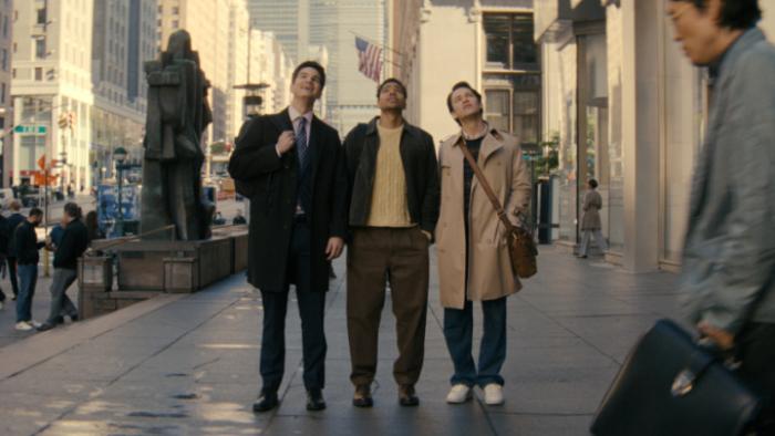 Not Suitable for Work TV show screenshot 1: Kel, Davis, and Josh stand on a New York City street arms around each other, looking up at buildings 