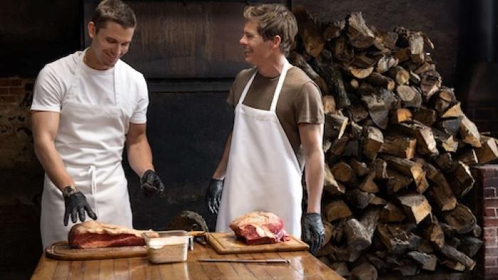 No Taste Like Home with Antoni Porowski TV show screenshot 3: Porowski and James Marsden wear aprons while standing at a table laden with raw meat