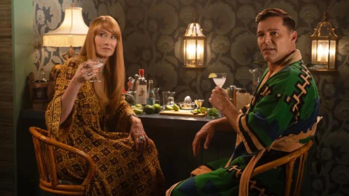 Palm Royale TV show screenshot 2: Linda and Robert wear robes and drink cocktails as they sit in front of a home bar