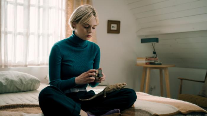 Patience TV show screenshot 1: Patience sits on a bed and looks down at a Rubik's cube she's solving
