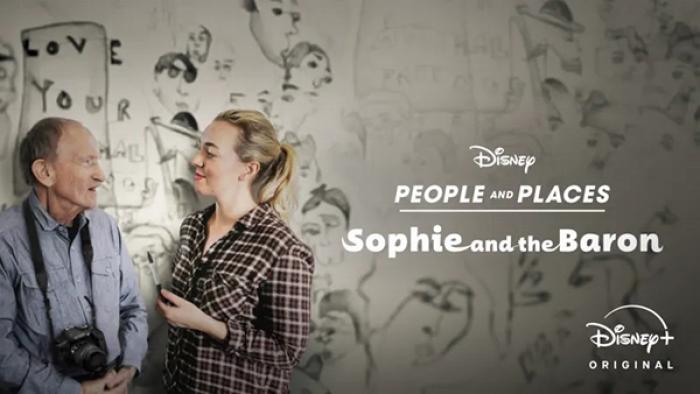 Pic from the People & Places ep Sophie and the Baron shows the artist duo smiling at each other in front of a sketchy black and white mural