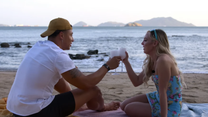 Perfect Match TV show: Chase and Kariselle sit on beach and toast each other with champagne.