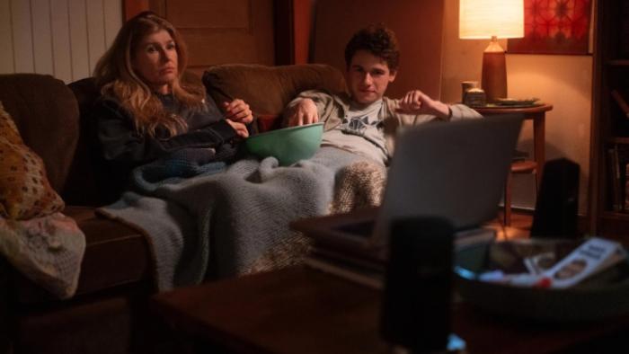 Phony TV show screenshot 1: Ellen and Sonny sit companionably together in their living room, sharing popcorn and watching something on TV