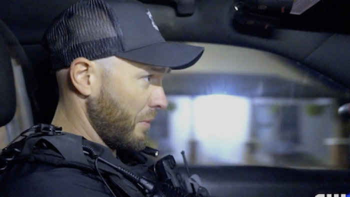 Police 24/7 TV show screenshot 1: Police officer in black cap drives and talks into police com. 
