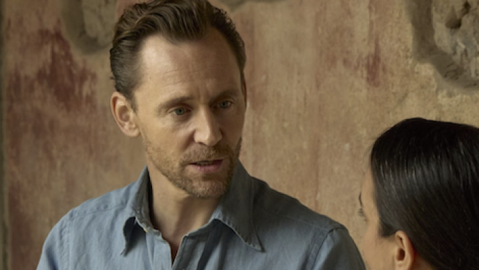 Pompeii: Out of Time with Tom Hiddleston screenshot 3: Hiddleston in a denim shirt talking to a woman against a textured wall.