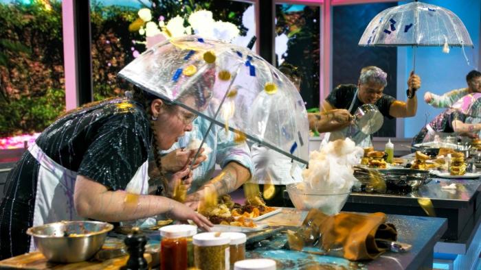Recipe for Disaster TV show screenshot 1: contestants duck under umbrellas while cooking