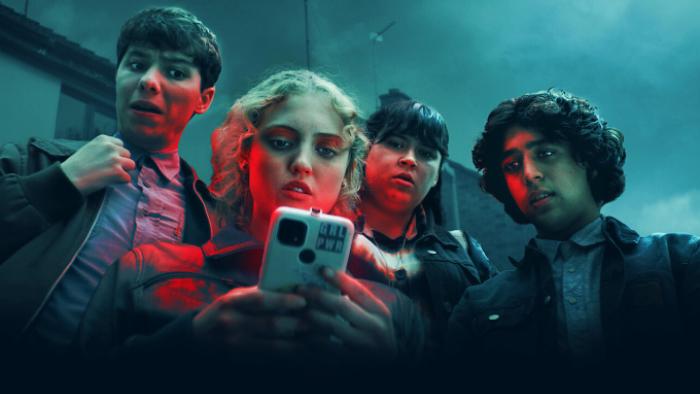 Red Rose TV show: Wren, Antony, Ash, and Tax stare at a phone together; they wear school uniforms and are grouped together beneath a forbidding sky