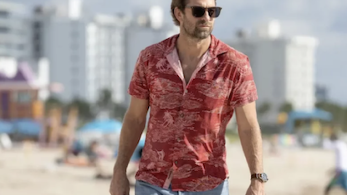 R.J. Decker TV show screenshot 1: R.J. Decker wears red shirt and walks on beach.