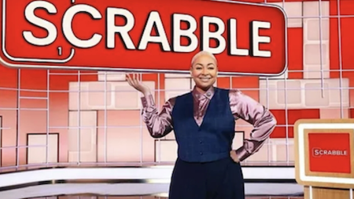 Scrabble TV show screenshot 1: Raven-Symoné stands smiling on game stage. 