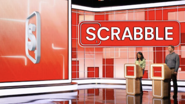 Scrabble TV show screenshot 2: Two contestants behind podiums look at digital board. 