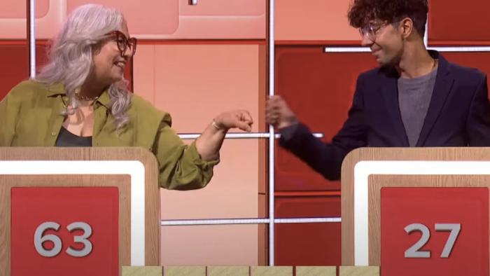 Scrabble TV show screenshot 3: Two contestants behind podiums fist bump eachother.