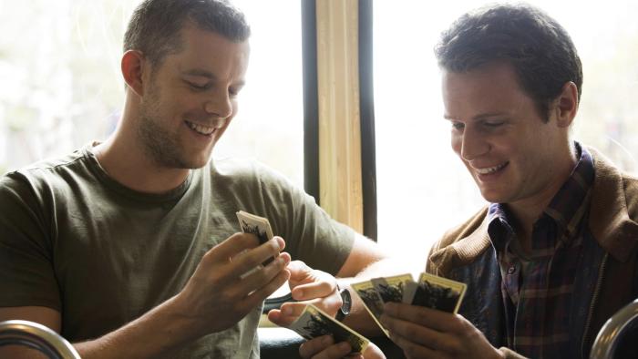 Looking TV Show: Two White men smile and look down at Polaroid photos, backlit in soft light