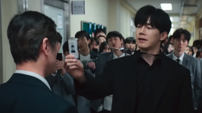 Teach You A Lesson TV show screenshot 1: Classroom hallway confrontation, man holds a badge toward another's face, crowd watches.
