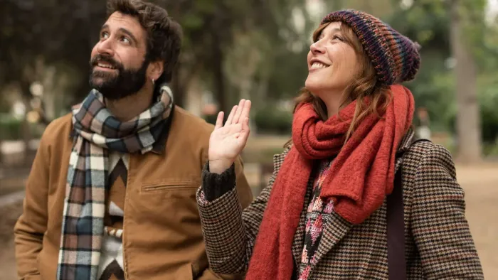 Shared Custody TV: Diego and Cris stand in an outdoor park wearing Fall outfits. They look up to the left and smile.