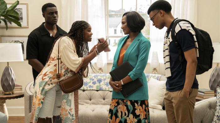 (From L-R) Philip Fornah, Drew Olivia Tillman, Terri J. Vaughn, and Tré Boyd in a living room. Tillman shows a phone to Vaughn.