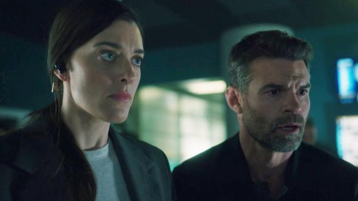 Sight Unseen TV show screenshot: A woman with an earpiece stands next to a man looking at something off screen.