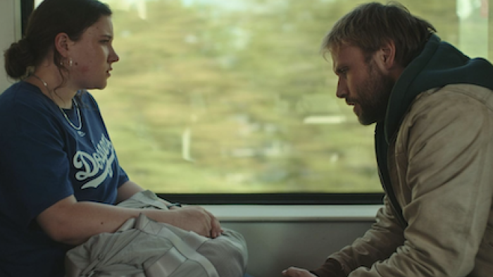 Sleeping Dog screenshot 3: Mike sits across from Tinka on a train. 