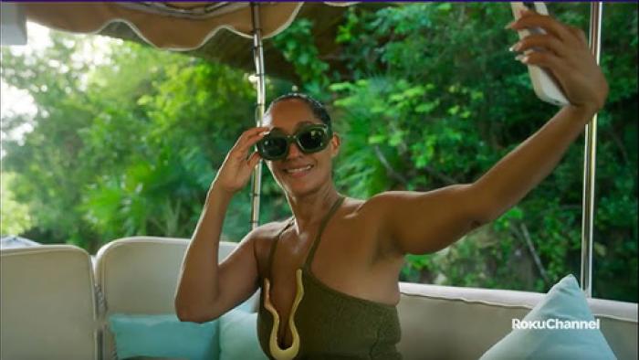 Solo Traveling with Tracee Ellis Ross TV show screenshot 2: Ross sits on an outdoor sofa with sky blue pillows. She's posing for a selfie