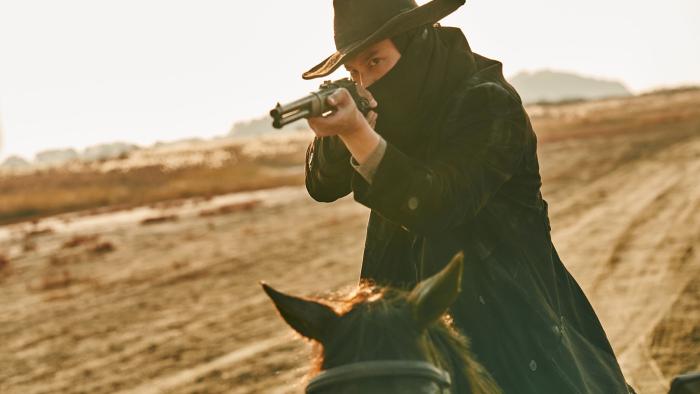 Song of the Bandits TV show screenshot: A man on hourse back aims a gun to the camera.