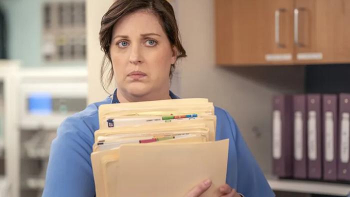 St. Denis Medical TV show screenshot 3: Alex holds a number of manila file folders and looks as if she's heard something she's not sure she likes